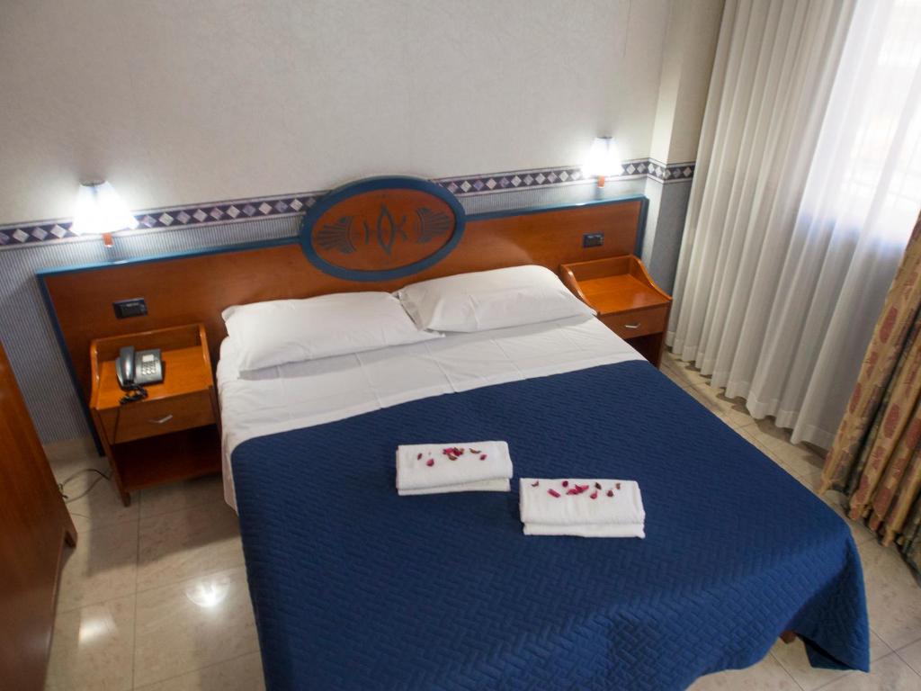 a bedroom with a blue bed with two white towels at Hotel Kroma in Ragusa