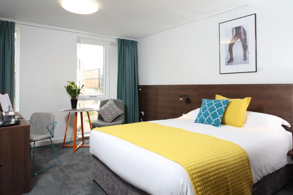 a bedroom with a large bed with a yellow blanket at Sunley Hotel in Northampton