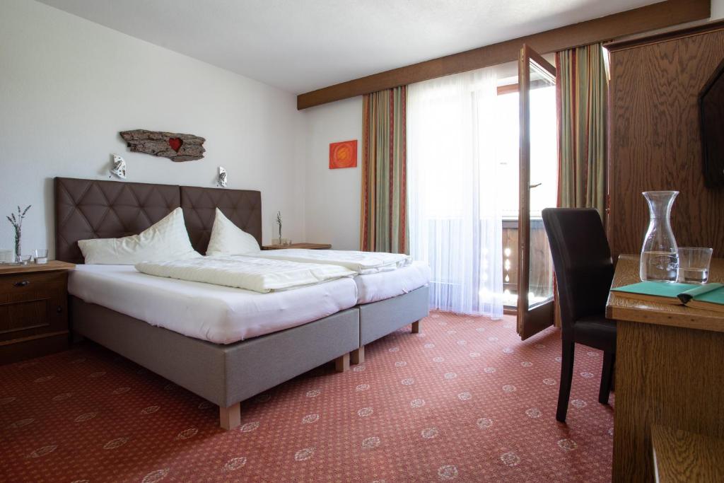 Helles und geräumiges Hotelzimmer im Ferienhotel Bergland mit Holzbalkon, Doppelbett und Bergblick
