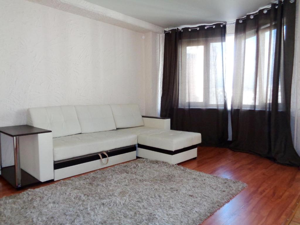 sala de estar con sofá blanco y alfombra en Apartments at Karla Marksa 21 en Krasnoyarsk