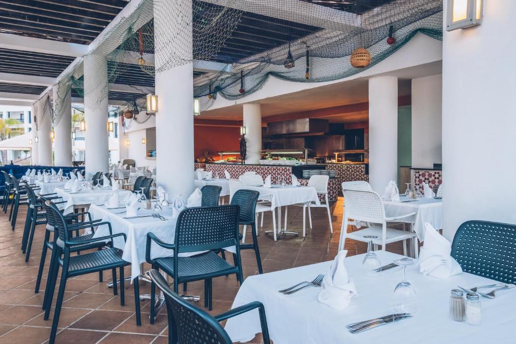 a dining room with white tables and chairs at Iberostar Waves Saidia in Saidia 
