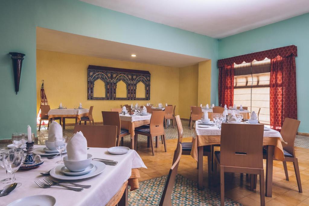 a dining room with tables and chairs with white table settings at Iberostar Waves Saidia in Saidia 