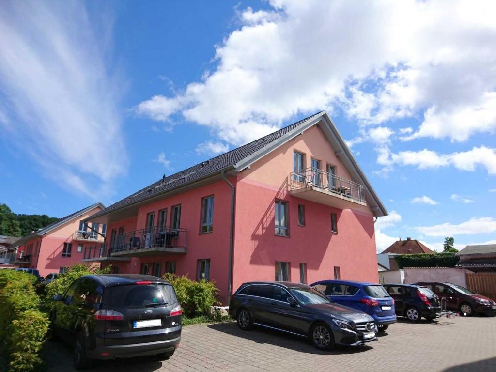 a pink building with cars parked in a parking lot at Haus Grete Wohnung 10 in Ostseebad Koserow