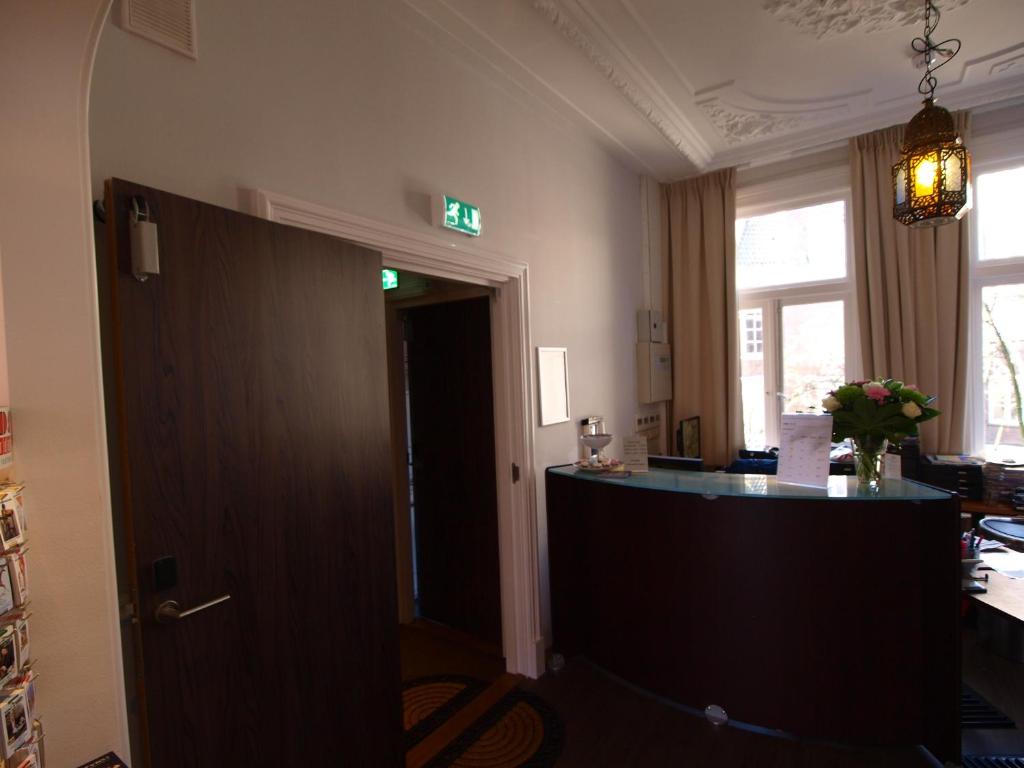 an office with a desk and a door with a green exit sign at Hotel Clemens in Amsterdam