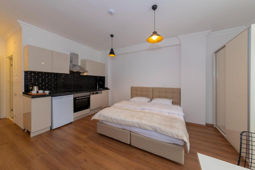 a white bedroom with a bed and a kitchen at Joy Suites in Istanbul