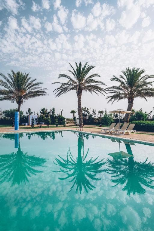 a swimming pool with palm trees in the background at Iberostar Waves Saidia in Saidia 