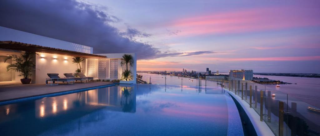 a swimming pool with a view of a city at night at Hotel Emion Phnom Penh in Phnom Penh