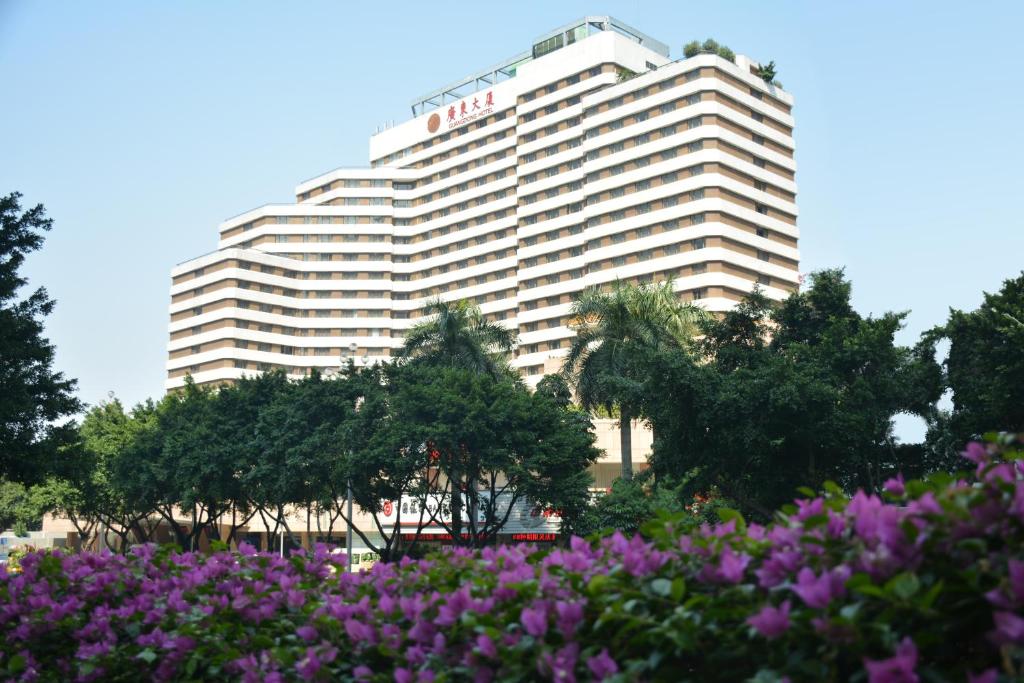 ein großes Gebäude mit lila Blumen davor in der Unterkunft Guangdong Hotel in Guangzhou