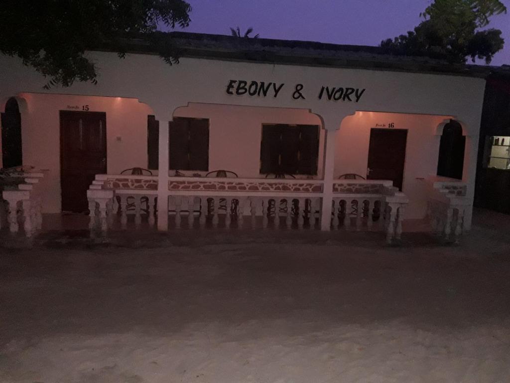 a white building with chairs outside at night at Ebony & Ivory Beach Bungalows in Nungwi