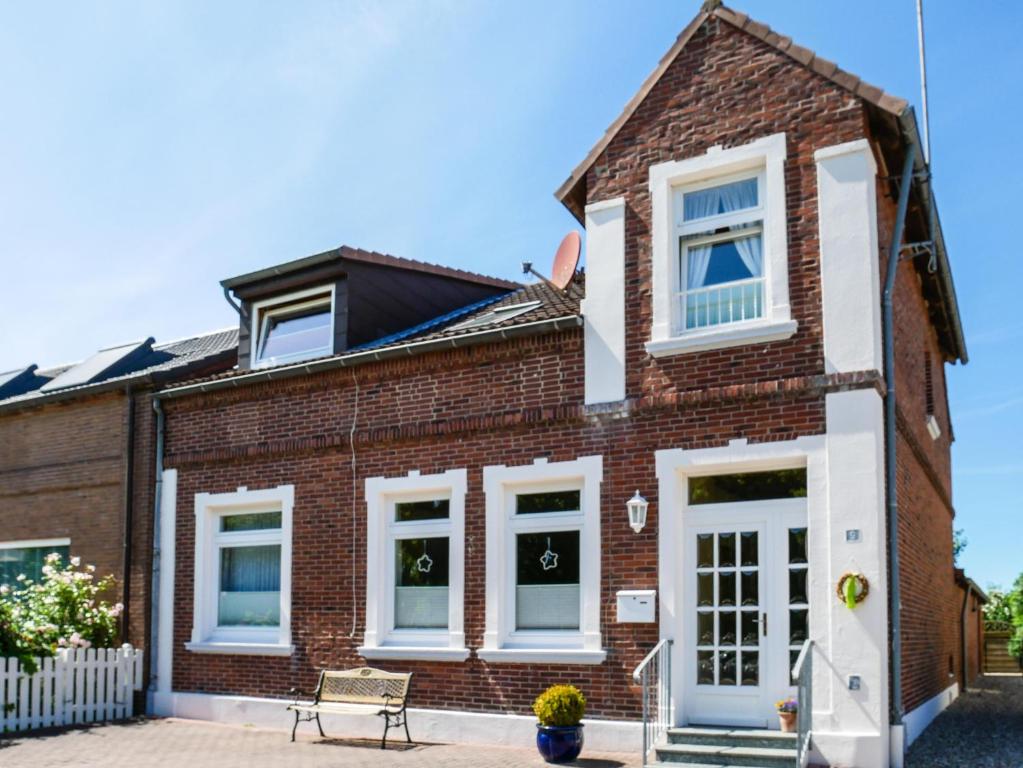 una casa de ladrillo con ventanas blancas y un banco en Ferienwohnung am Dorfteich en Fehmarn