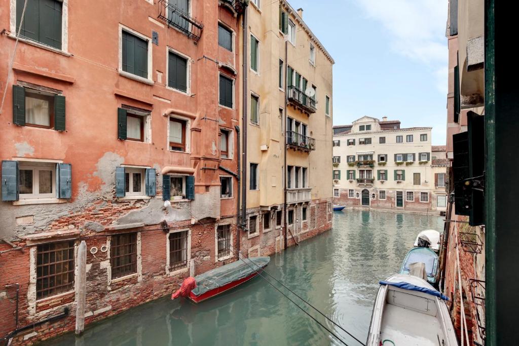 un bateau dans un canal entre deux bâtiments dans l'établissement Cannaregio Canal View - Marco Polo, à Venise