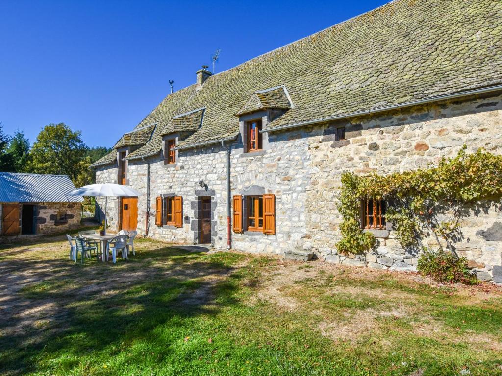 uma casa de pedra com uma mesa e um guarda-chuva em Comfy holiday home with private garden em Neuvéglise