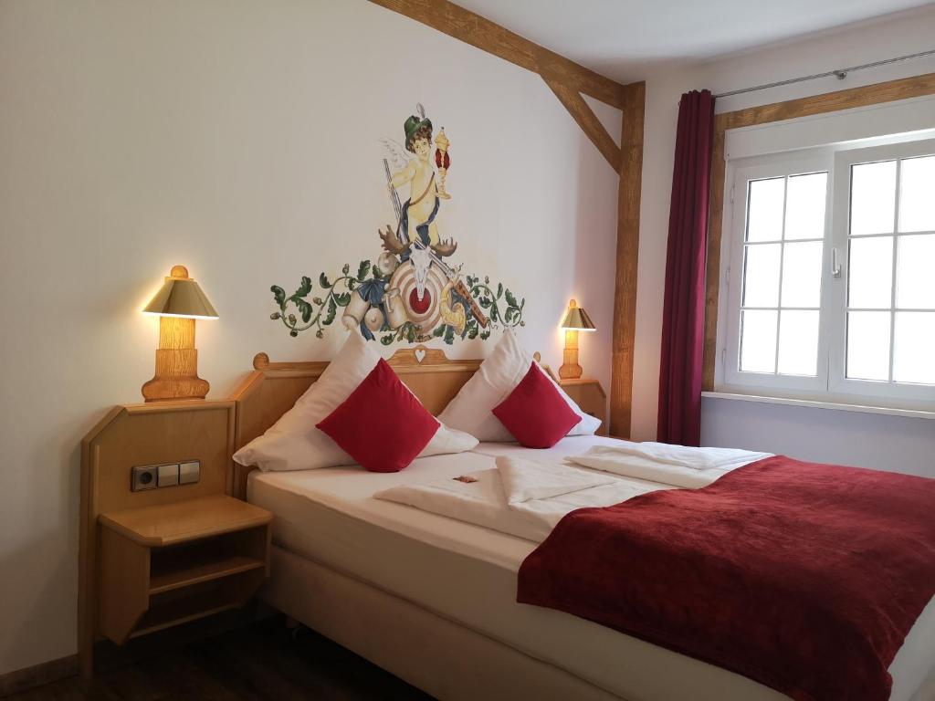 um quarto com uma cama grande e lençóis vermelhos em Hotel DreiKönig & Restaurant SeeGourmet em Hagnau