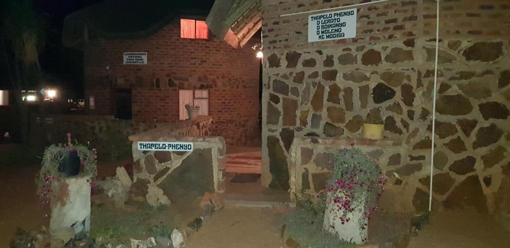 una habitación con una pared de piedra y algunas plantas en Gae Lodge, en Ganyesa