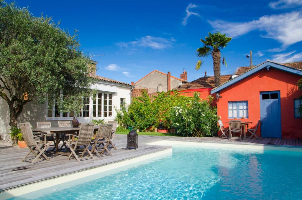 een huis met een zwembad en een tafel en stoelen bij La Ferrade Chambres d'Hôtes B&B in Bègles