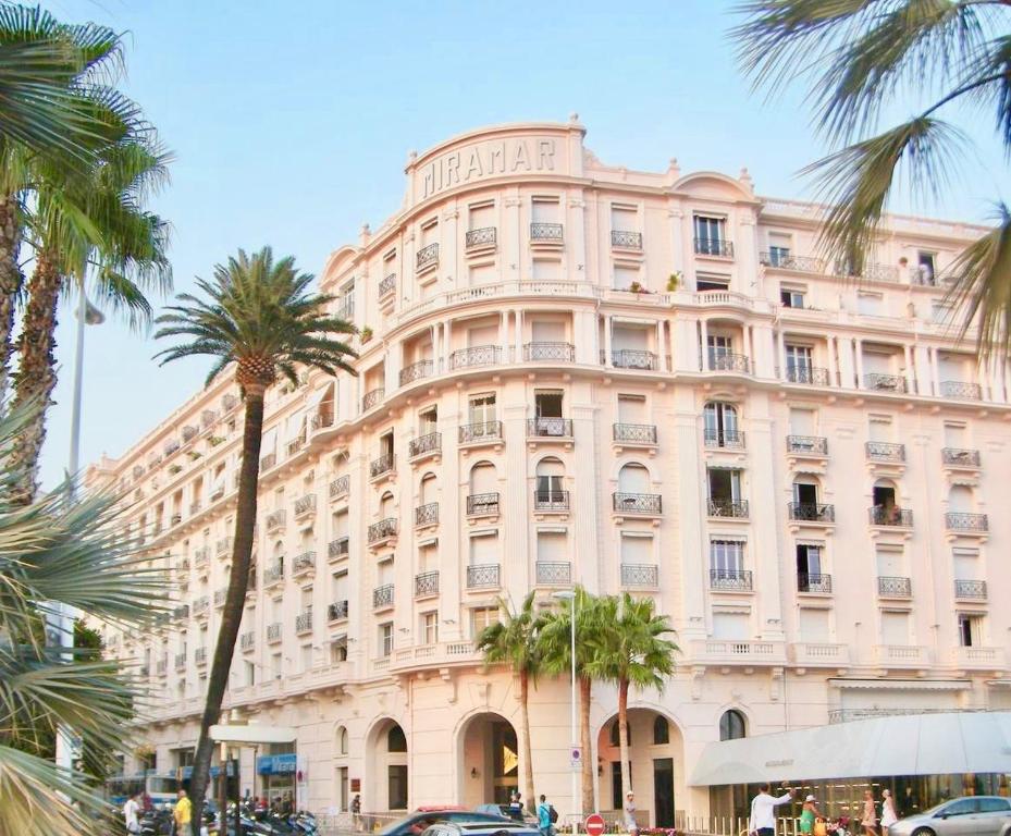 a large building with palm trees in front of it at New - cosy & nice Apartment in Palais Miramar in Cannes