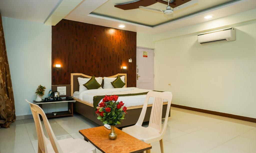 Un dormitorio con una cama y una mesa con un jarrón de flores en Treebo Trend Hillway Inn Main Market, en Mahabaleshwar