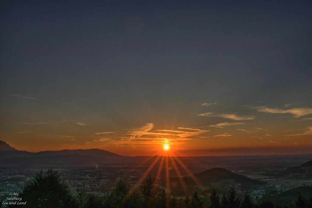 a sunset with the sun setting over a city at Panoramagasthof DaxLueg in Salzburg