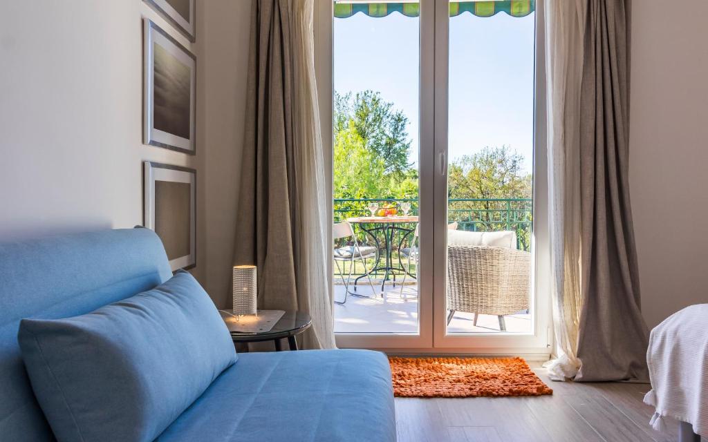 - un salon avec un canapé bleu et une porte coulissante en verre dans l'établissement Apartman Bellavista, à Pula