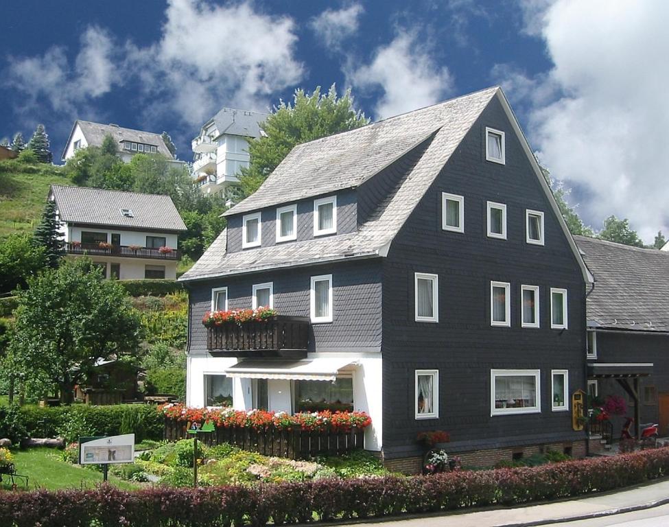 una casa en blanco y negro con flores en un patio en Ferienwohnungen Schäferhaus, incl MeineCardPlus, en Willingen