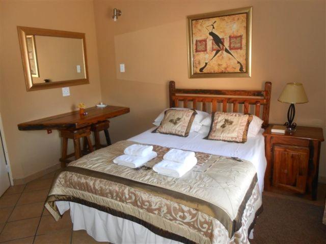 a bedroom with a bed with two pillows on it at Platinum Lodge Polokwane in Polokwane