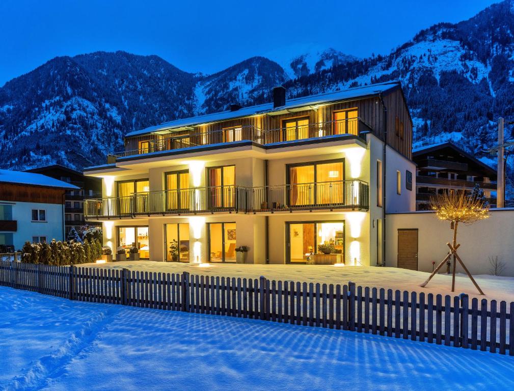 una casa en la nieve por la noche con montañas en Fuchs Apartments - inklusive Eintritt in die Alpentherme Gastein, en Bad Hofgastein