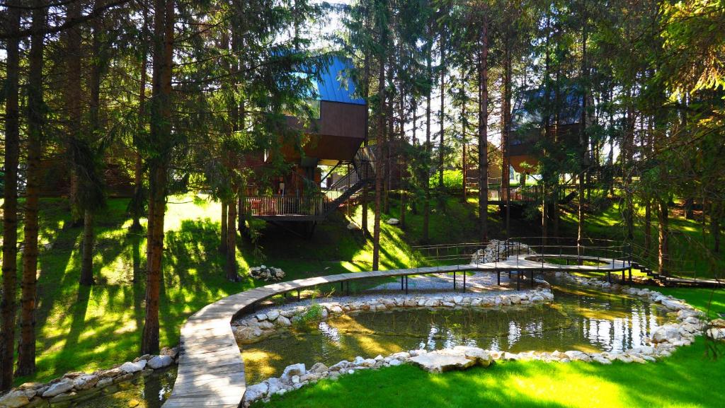 a bridge over a pond in a park with trees at Plitvice Holiday Resort in Grabovac