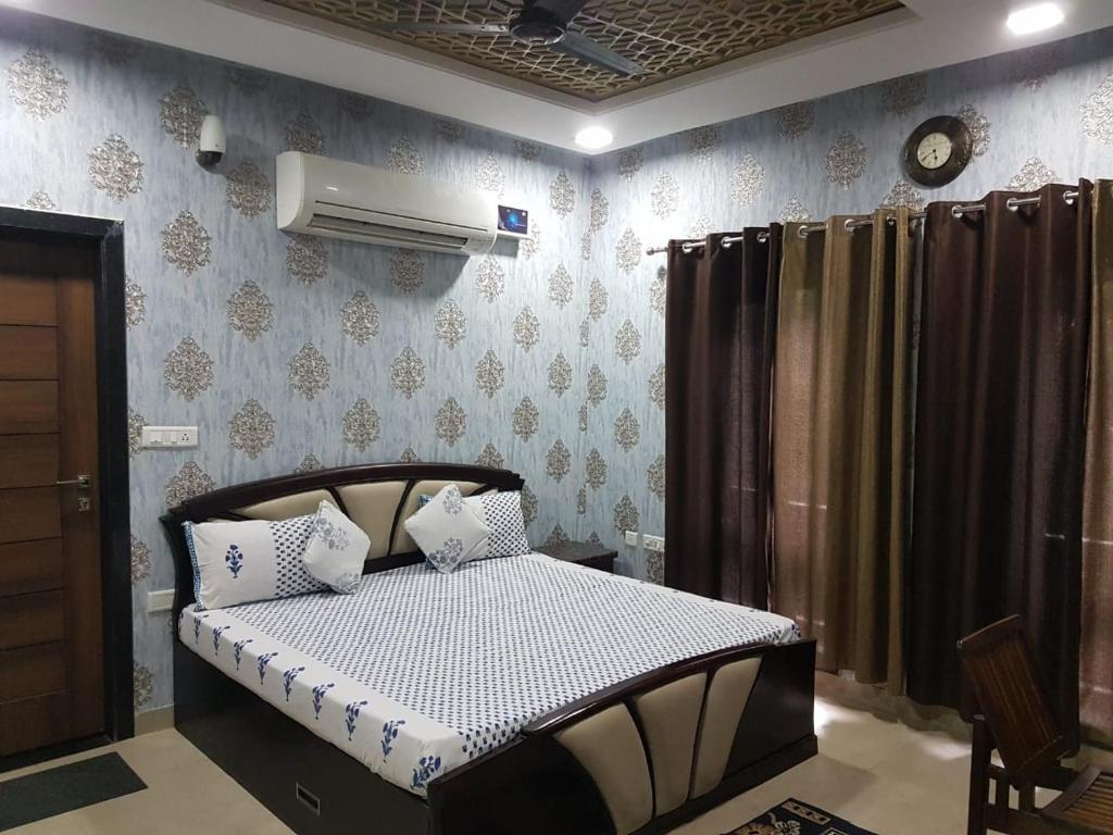 ジャイプールにあるNeetu's Home Stayのベッドルーム1室(ベッド1台、壁掛け時計付)