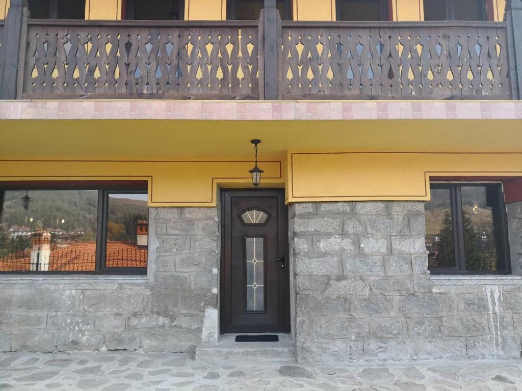 a building with a black door and windows at Yurukovata kashta in Koprivshtitsa