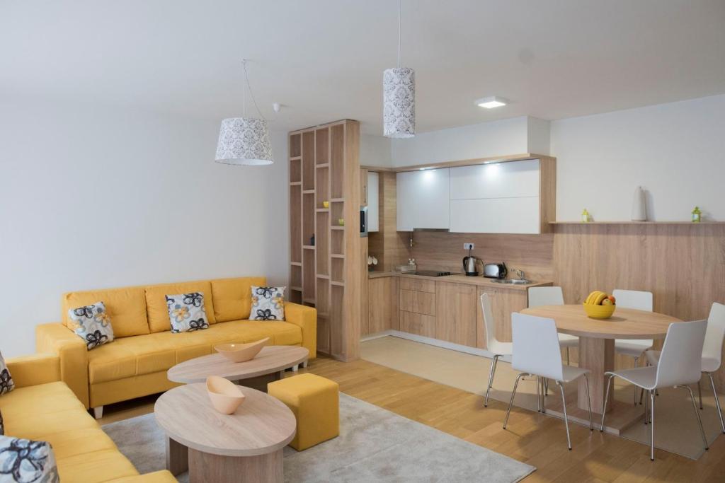 a living room with a yellow couch and a kitchen at Turistic Apartments Centar Sarajevo in Sarajevo