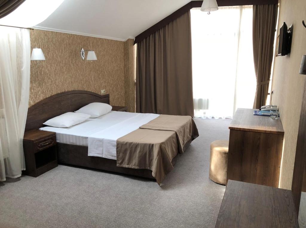 クラスノダールにあるОтель-сауна Messalinaのベッドと大きな窓が備わるホテルルームです。