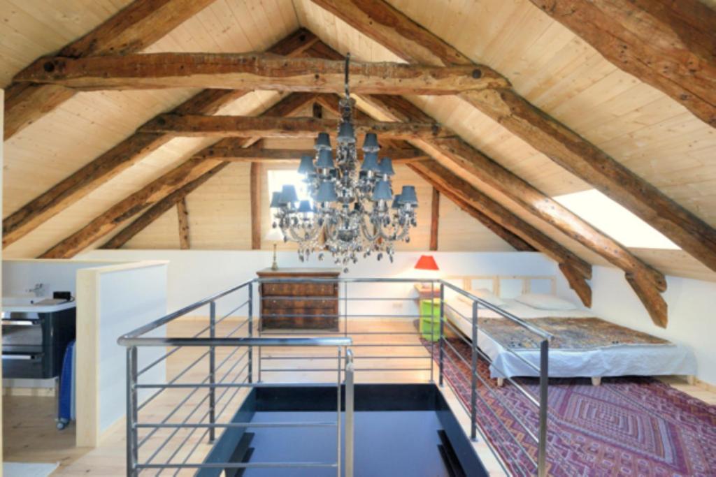 Habitación con altillo con cama y lámpara de araña. en La Drapière, en Fay-sur-Lignon
