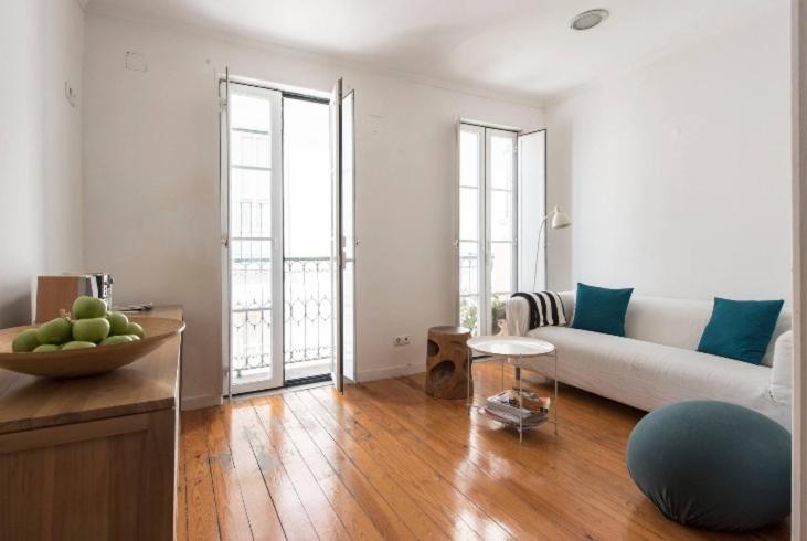 uma sala de estar com um sofá branco e piso em madeira em Cosy Alfama em Lisboa