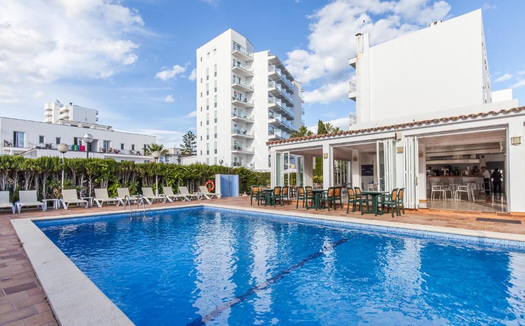 a pool with chairs and tables and a building at BLUESEA Cala Millor in Cala Millor