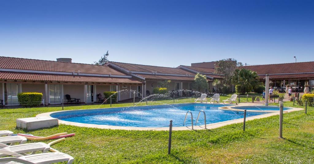 a swimming pool in a yard with lawn chairs at Club Valle Termal Resort in Federación
