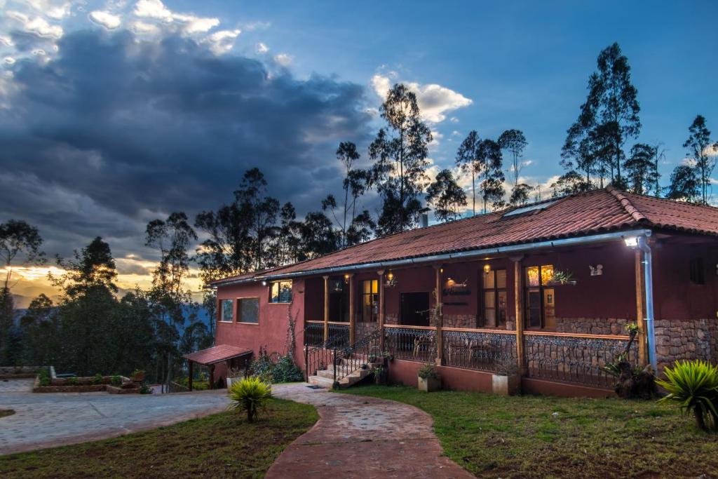 a house with the sunset in the background at La Ensenada Hotel Chachapoyas in Chachapoyas