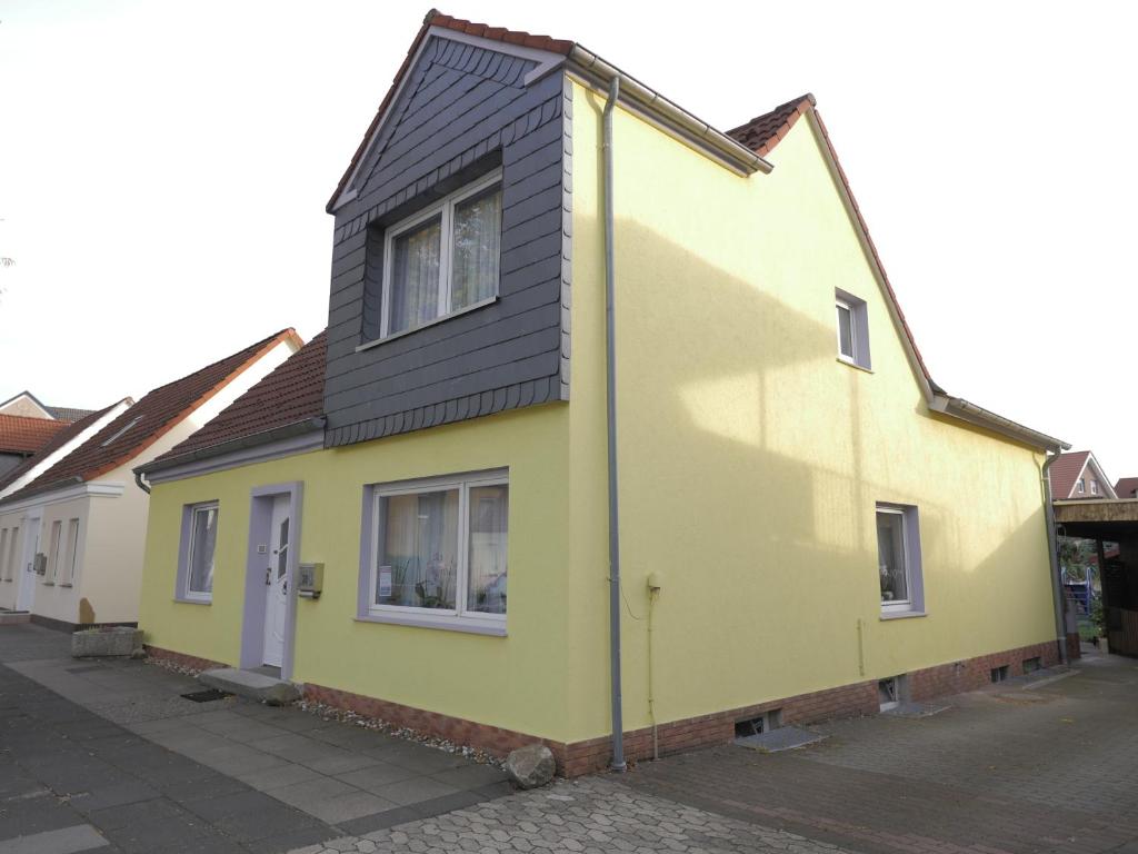 a yellow house with a black roof on a street at Zimmervermietung am Teutoburger Wald in Lage