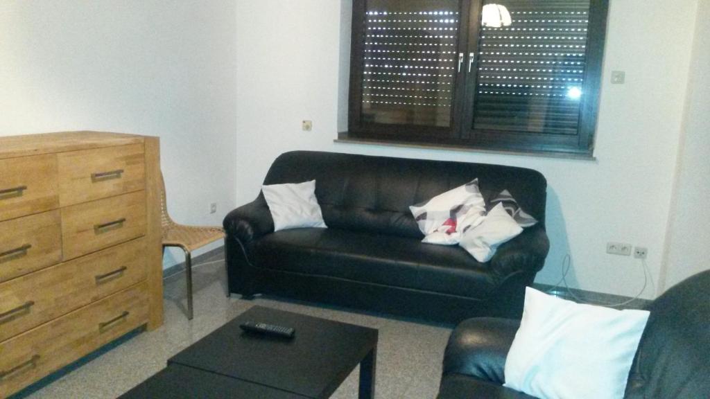 ein Wohnzimmer mit einem schwarzen Ledersofa und einer Kommode in der Unterkunft Ferienwohnung Klaus in Oberhausen