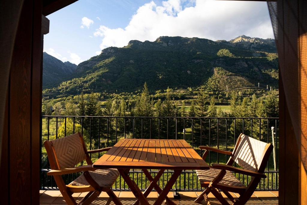 a table and chairs on a balcony with a view of a mountain at Inmocyma Abetal grandes vistas, con piscina-Linsoles- Benasque in Benasque