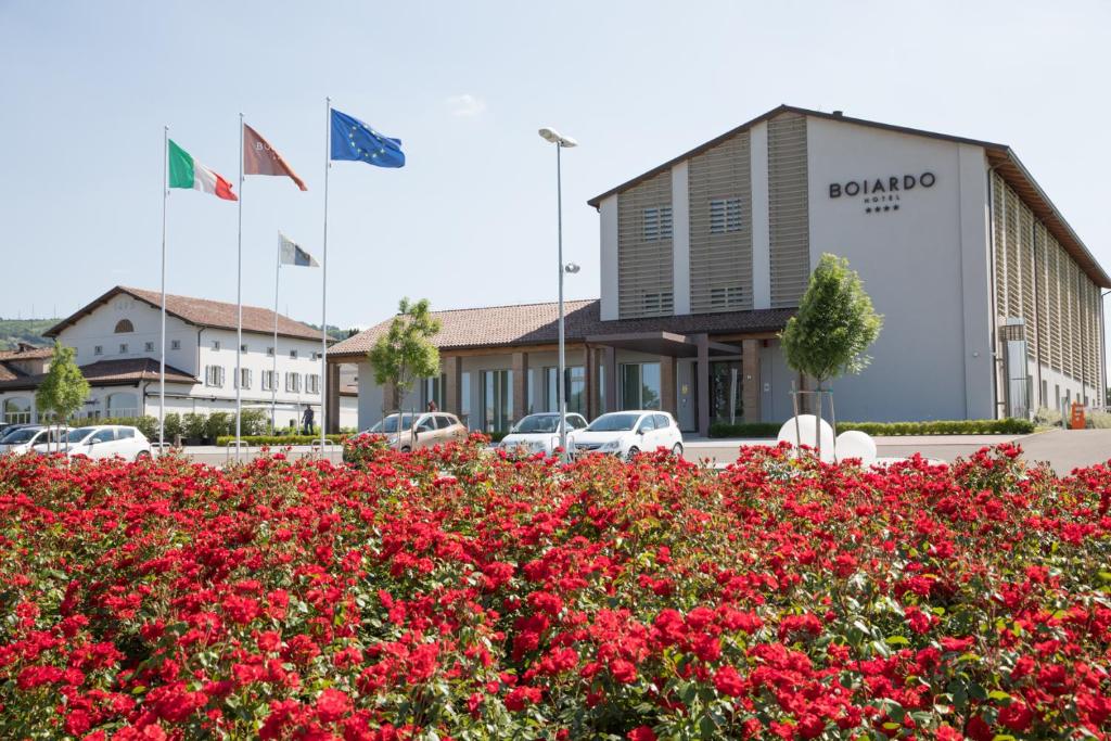 ein Parkplatz mit roten Blumen vor einem Gebäude in der Unterkunft Boiardo Hotel in Scandiano