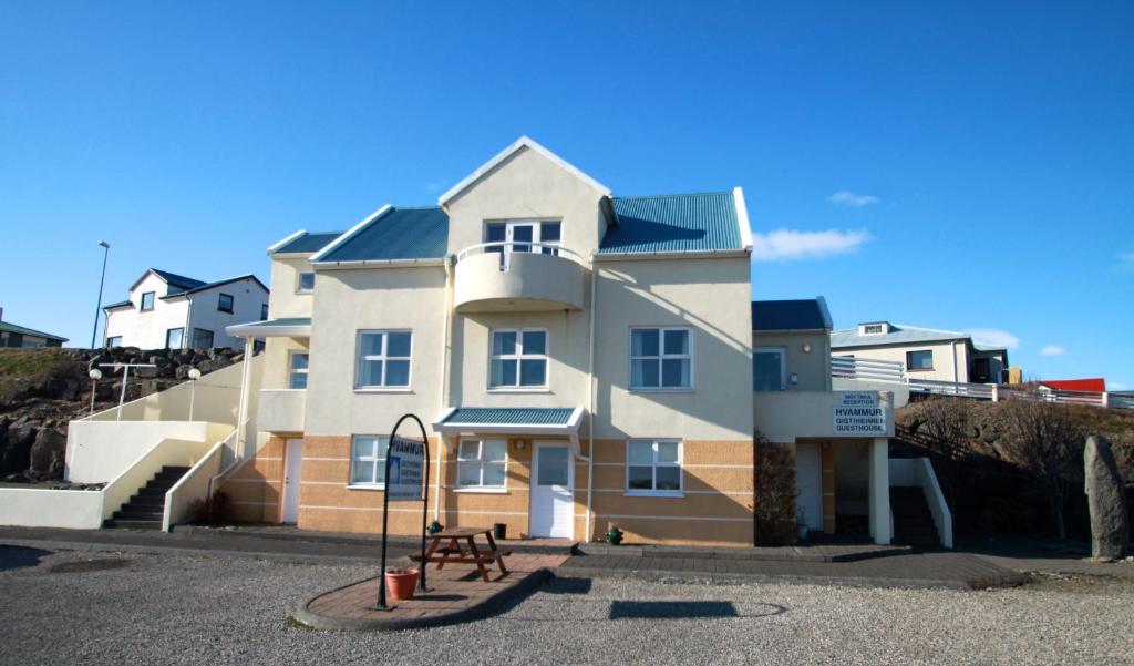 a large white house with a bench in front of it at Guesthouse Hvammur in Höfn