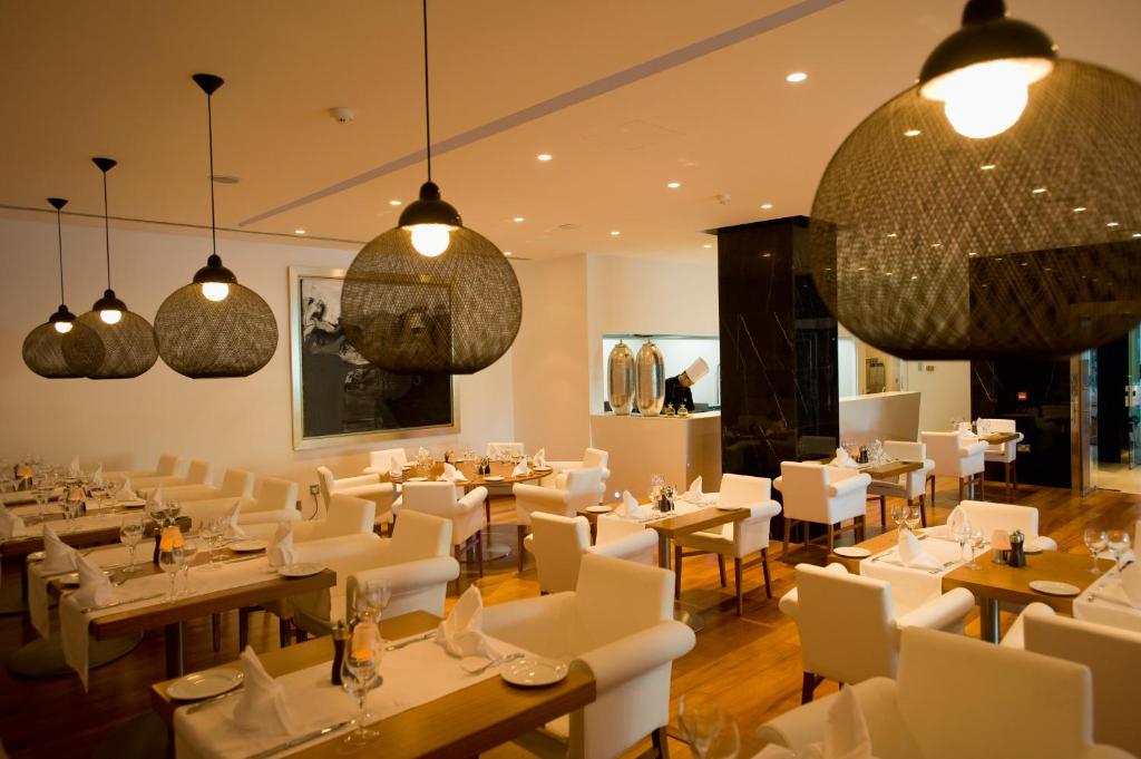 a restaurant with white tables and chairs and chandeliers at Mediterranean Beach Hotel in Limassol