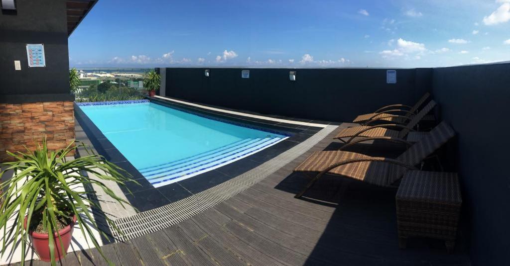a large swimming pool on a building with chairs at Simply Comfy 916 (Cityscape Bacolod) in Bacolod
