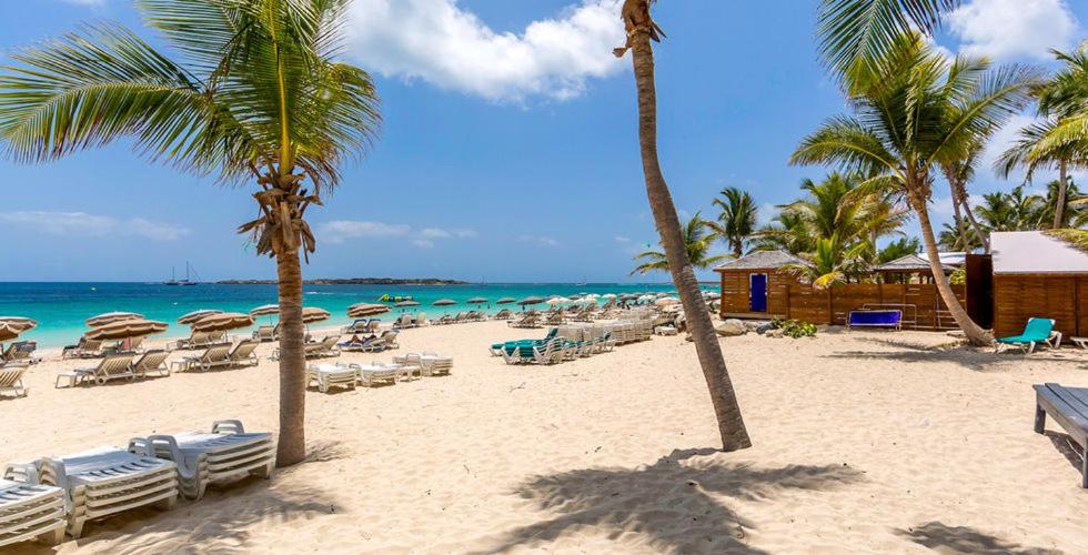 una playa con sillas y sombrillas y el océano en Résidence La Plage Orient Bay by La Conciergerie FWI, en Saint Martin