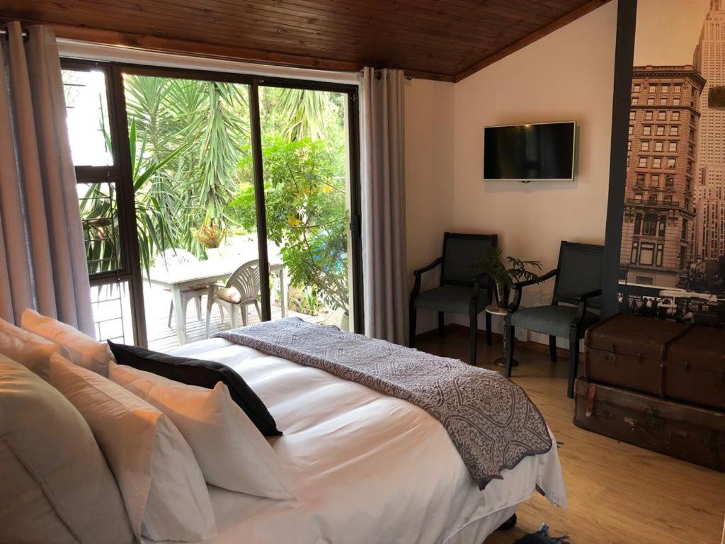 een slaapkamer met een bed en een groot raam bij The Wild Fig in Durbanville