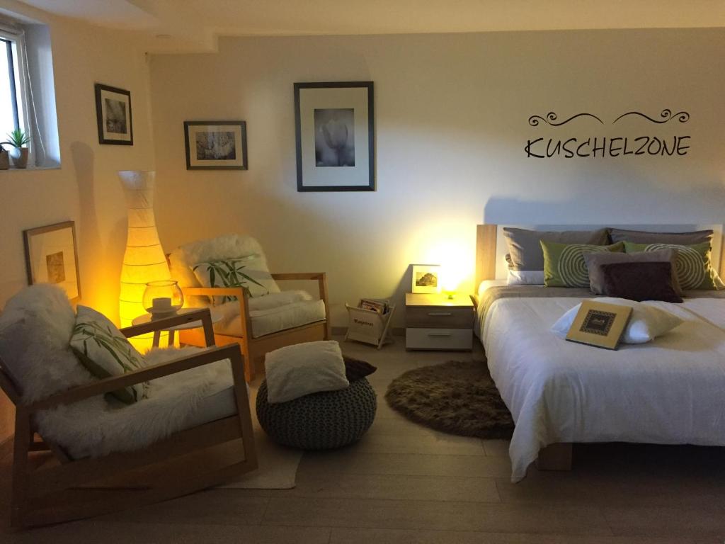 a bedroom with two beds and a chair and a lamp at Schwarzwald Boutique-Apartment HAUS REHGARTEN in Gaggenau