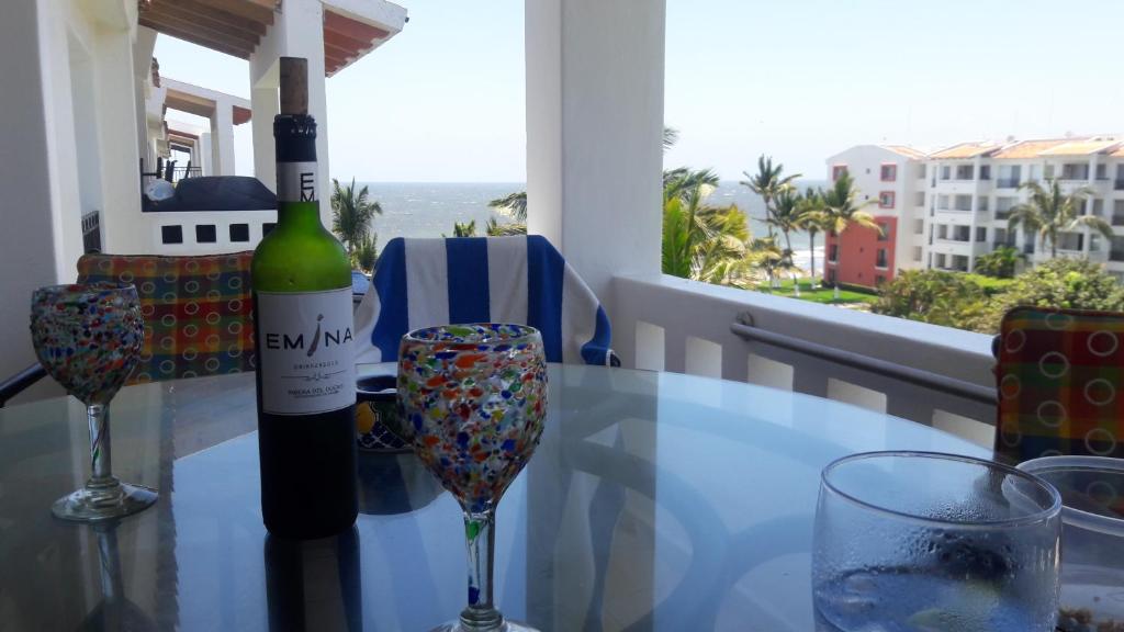 a glass table with a bottle of wine and two wine glasses at Apartamento Pelicanos, Nuevo Vallarta in Nuevo Vallarta