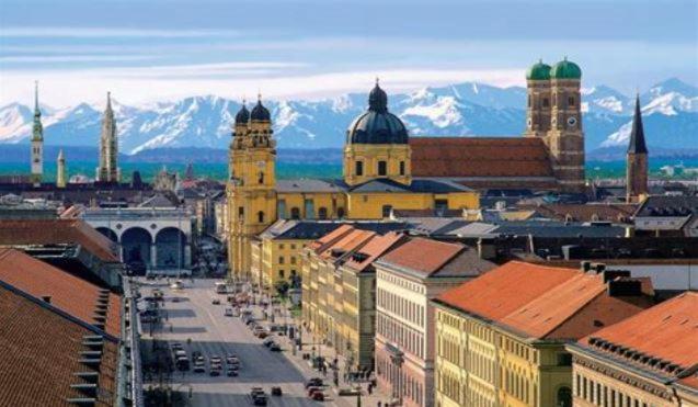 a city with buildings and mountains in the background at City Apartment Munich in Munich