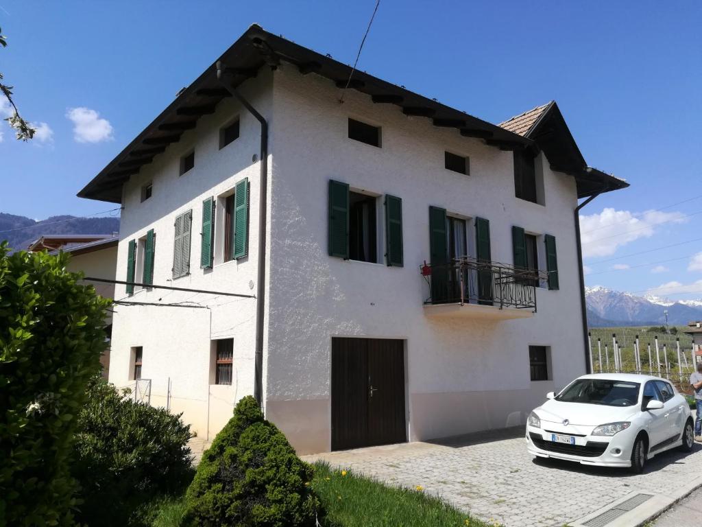 a white house with a car parked in front at MELAX Apartment in Tassullo