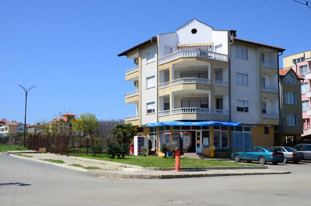 un edificio blanco alto con coches estacionados frente a él en Kirovi House - guest rooms, en Tsarevo